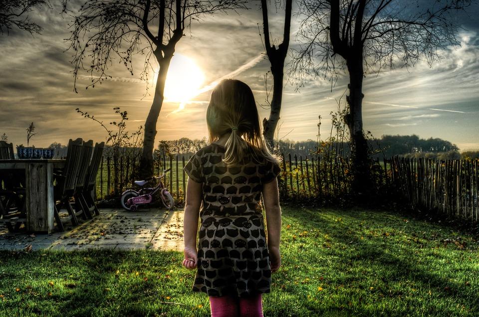 girl looking at fence in yard